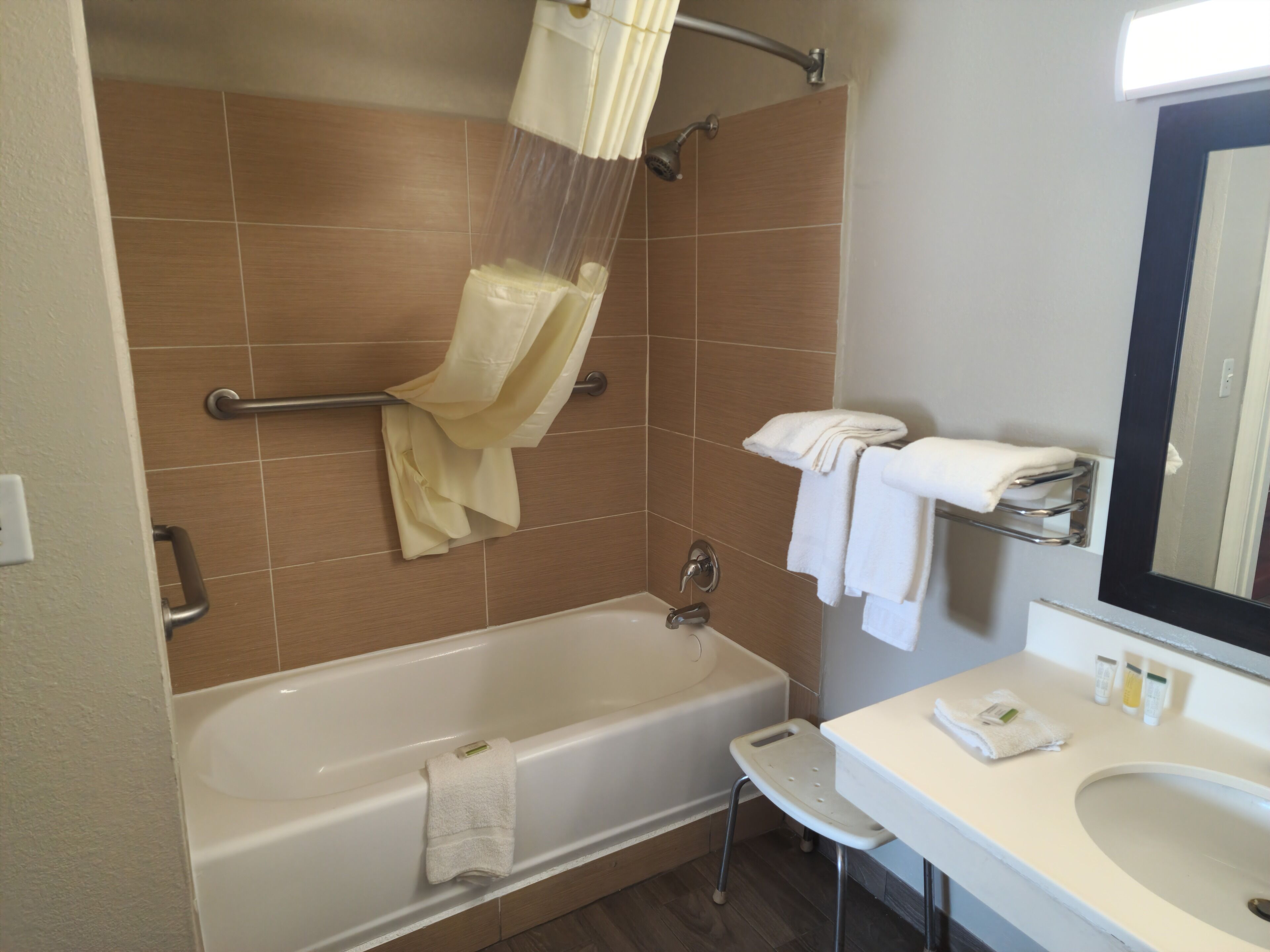 A bathroom with a bathtub, a shower, a sink, and a mirror.