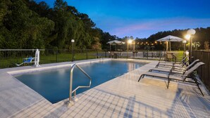 Ein rechteckiger Pool mit Metallleiter und Liegebereich mit Liegestühlen und Sonnenschirmen.