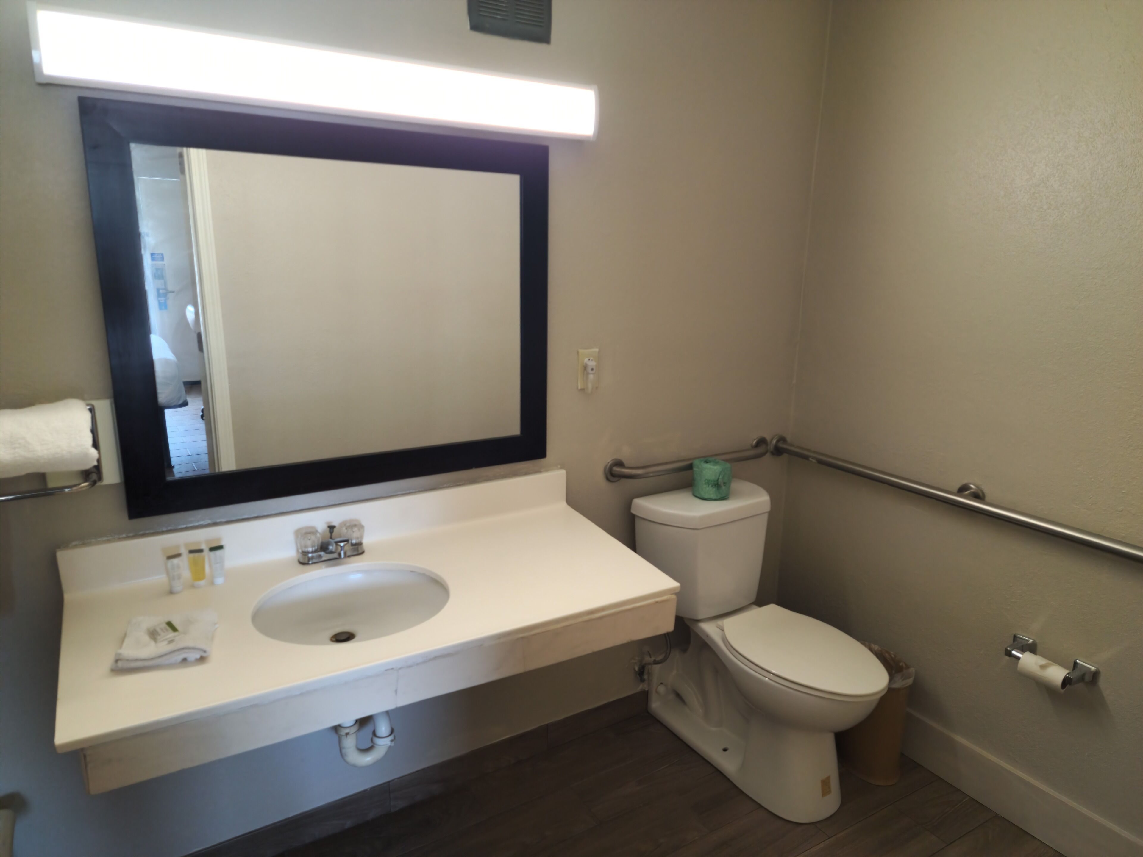 A bathroom with a white sink, mirror, and toilet.