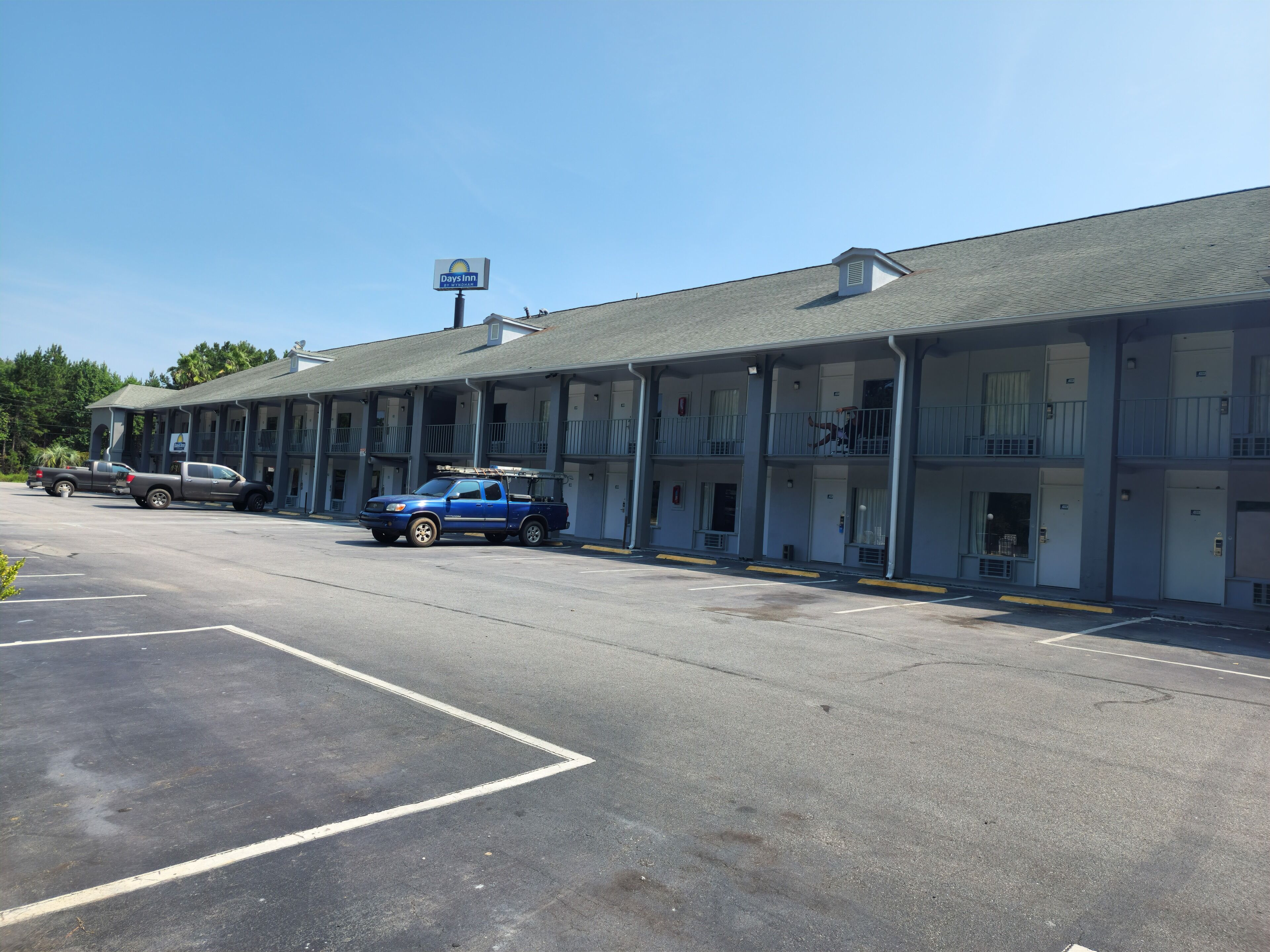 Un motel con estacionamiento, una camioneta pickup azul y un cartel de Days Inn.