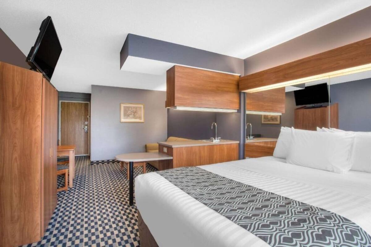 A hotel room with a bed, a desk, a chair, a TV, and a bathroom.