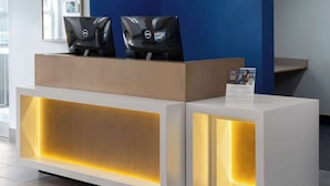 A reception desk with two monitors, a sign, and a blue wall in the background. - Microtel Inn & Suites by Wyndham Dover (Dover)