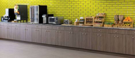 A kitchen area with a yellow brick wall, wooden cabinets, and various appliances like a microwave, toaster, and coffee maker.