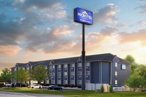 Edificio de Microtel Inn & Suites con fachada azul, varias ventanas y un estacionamiento con automóviles.