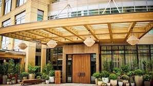 A hotel entrance with a wooden canopy, potted plants, and a bench. - 1 Hotel Seattle (Seattle)