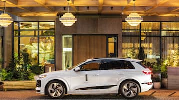 A white SUV parked in front of a building with a wooden facade and large windows.