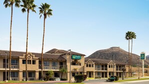 A hotel with a central entrance, multiple balconies, and palm trees. - Quality Inn Lake Elsinore I-15 (Lake Elsinore)