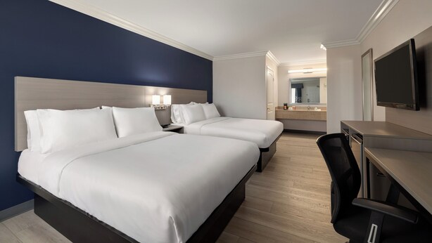 A hotel room with two beds, a desk, a chair, a TV, and a bathroom visible in the background. - Quality Inn Lake Elsinore I-15 (Lake Elsinore)