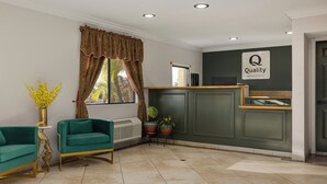 A reception area with a green wall, a reception desk, two sofas, and potted plants. - Quality Inn Lake Elsinore I-15 (Lake Elsinore)