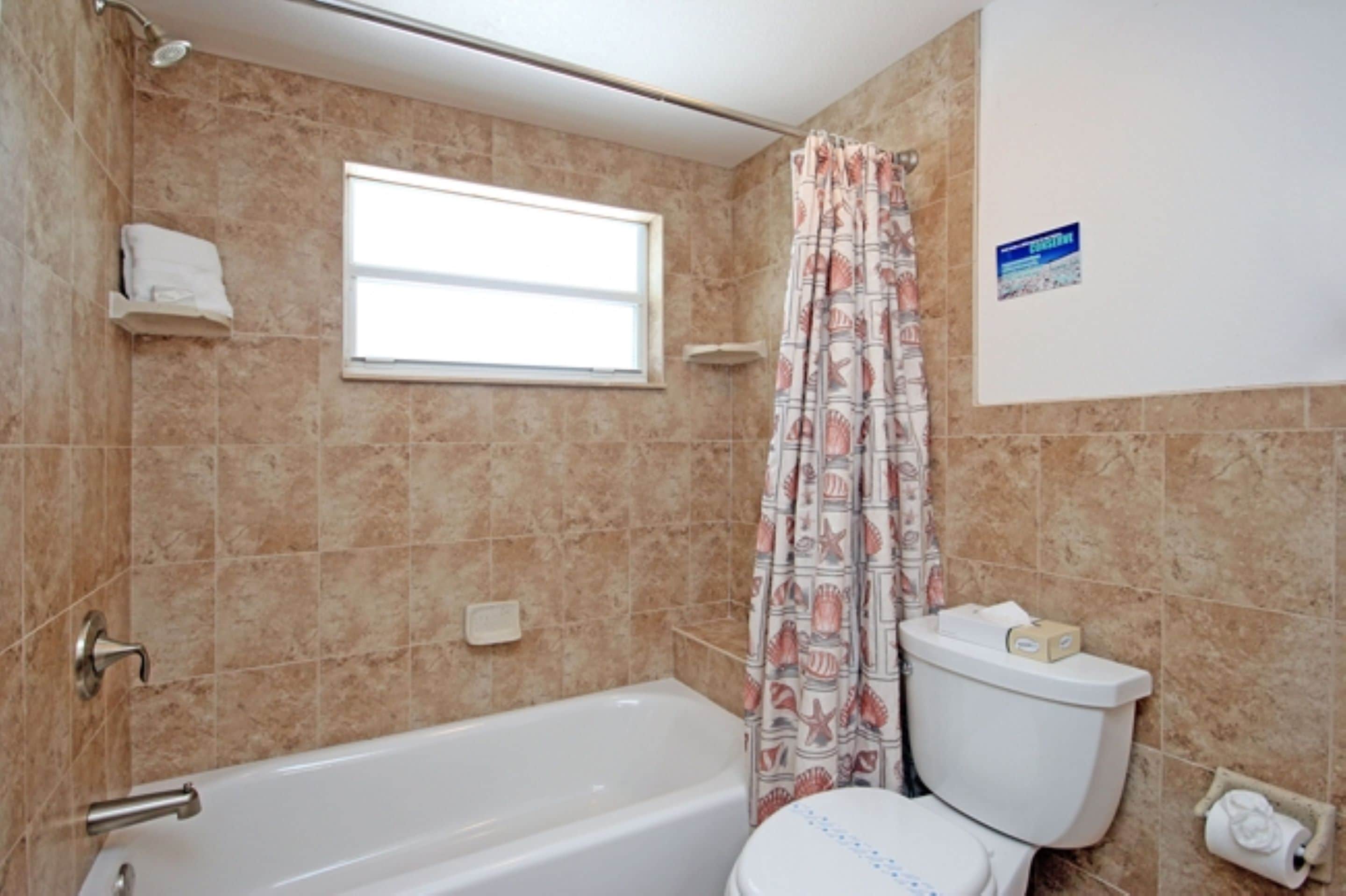 Un baño con bañera, inodoro y cortina de ducha.