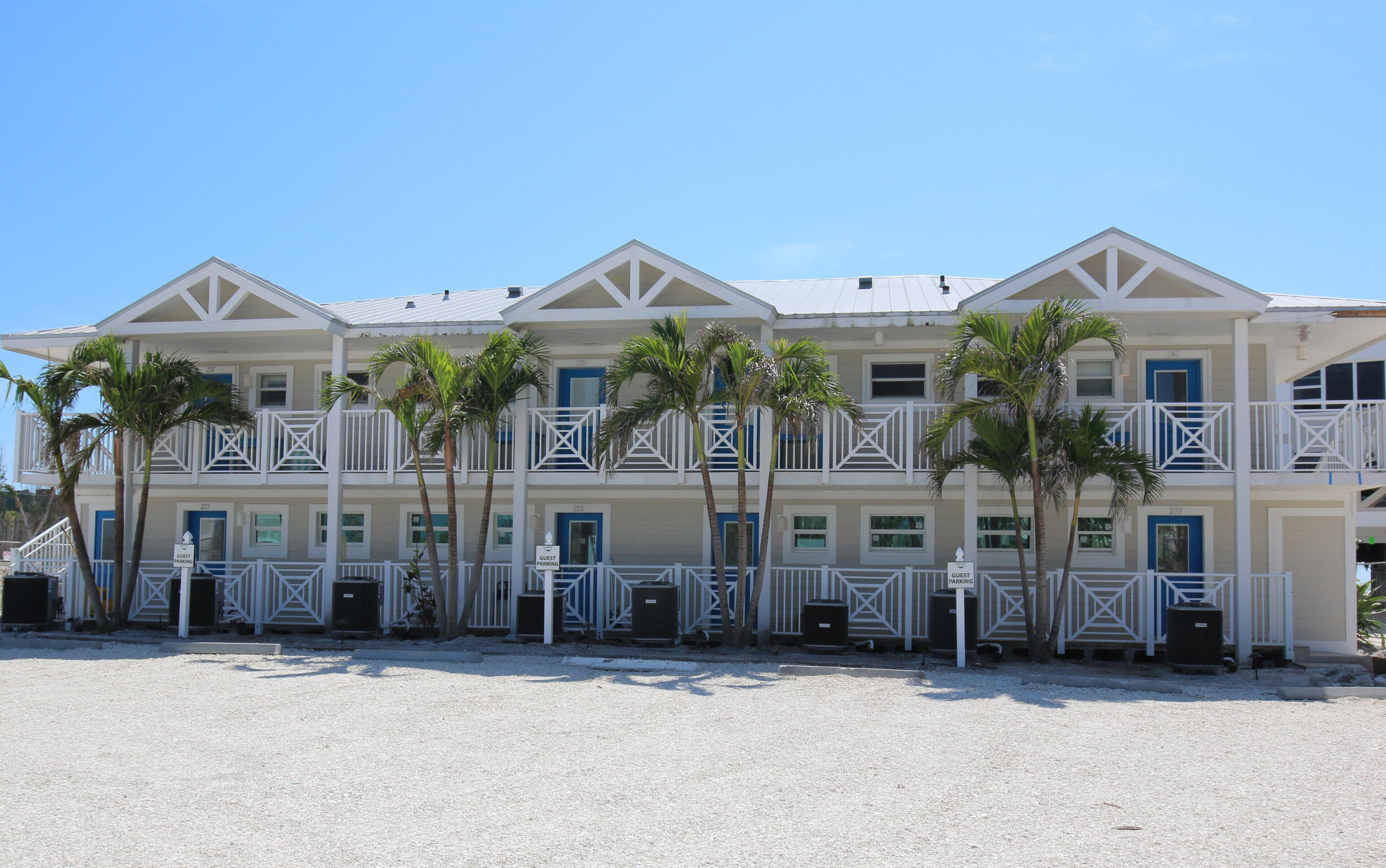 Un hôtel situé en bord de mer, doté de nombreux balcons, de palmiers et d’un parking réservé aux clients.