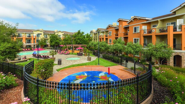 A courtyard with a swimming pool, lounge chairs, and a decorative fountain. - Vino Bello Resort (Napa)