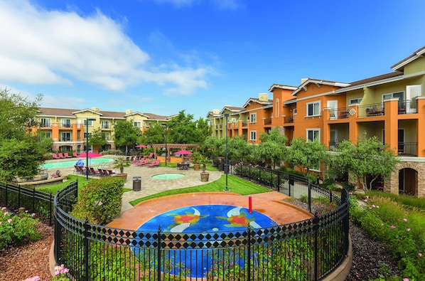 A courtyard with a swimming pool, lounge chairs, and a decorative fountain. - Vino Bello Resort (Napa)