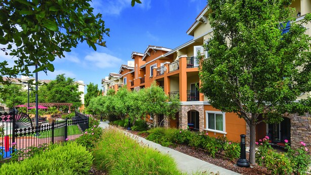 A residential building with multiple balconies, a paved walkway, and lush greenery. - Vino Bello Resort (Napa)