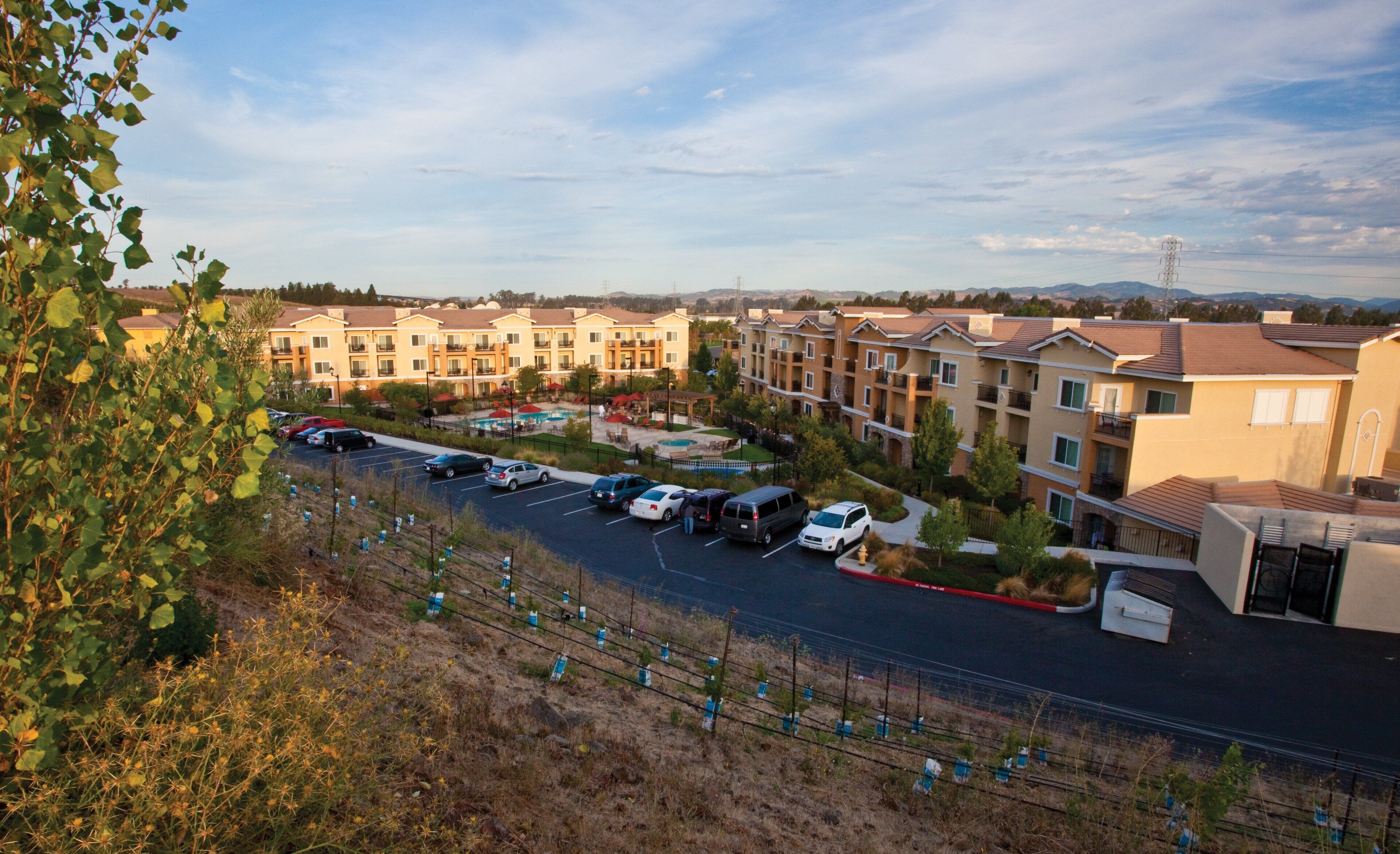 Zona residencial con edificios de apartamentos, un estacionamiento y una piscina.