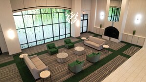A spacious lounge area with a large arched window, a fireplace, and several seating options including sofas and chairs.