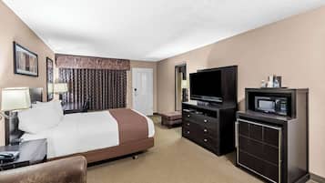 Una habitación de hotel con cama, televisión, microondas, cómoda y escritorio con lámpara.