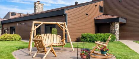 A modern house with a swing set and a rocking chair in the yard.