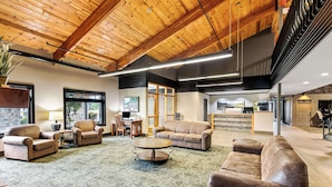 A spacious living area with leather sofas, a coffee table, and a stone accent wall. - Heartland Inn & Suites, SureStay Collection by Best Western (Park Rapids)
