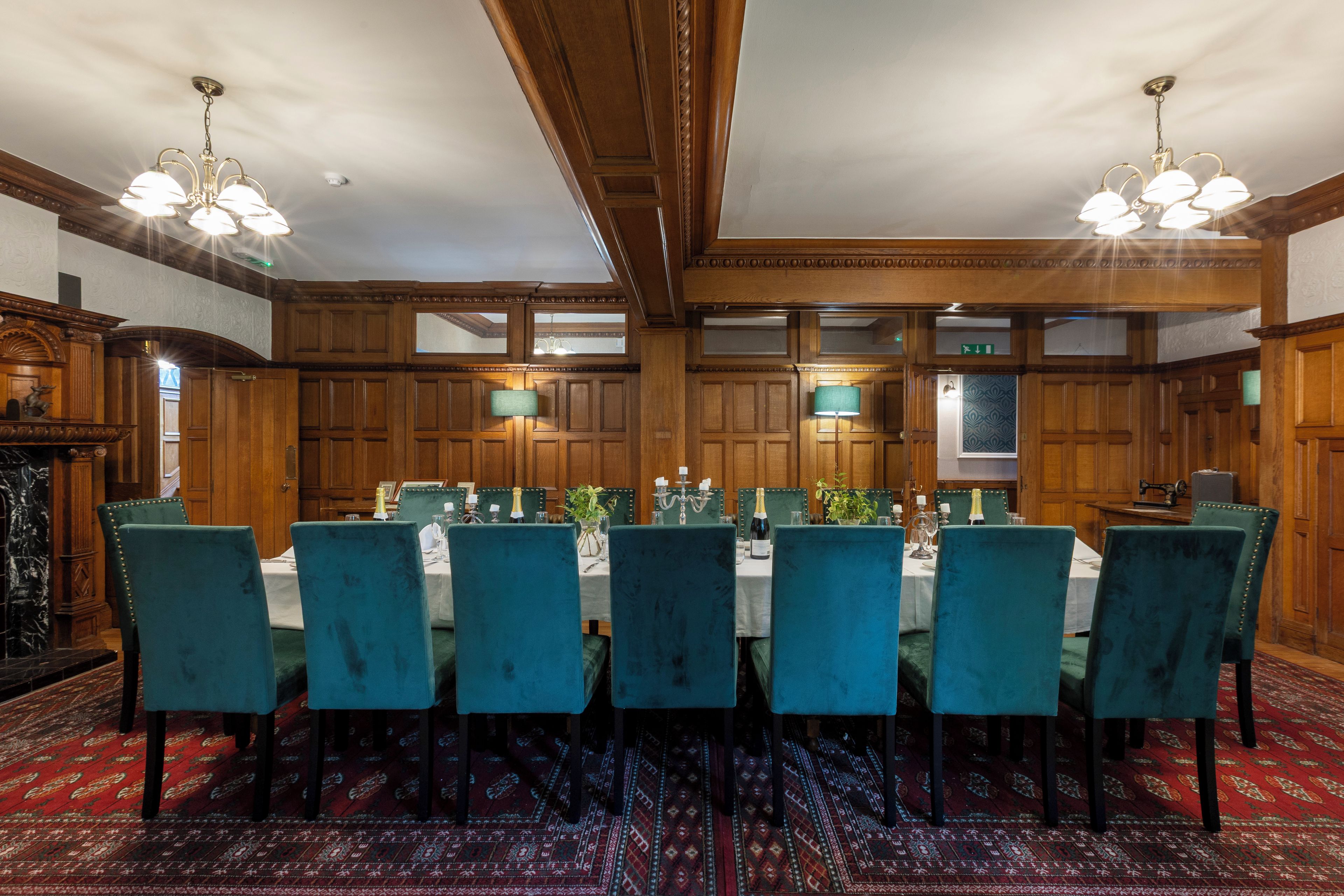 A formal dining room with a long table, multiple chairs, and chandeliers.