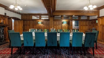 A formal dining room with a long table, multiple chairs, and chandeliers.