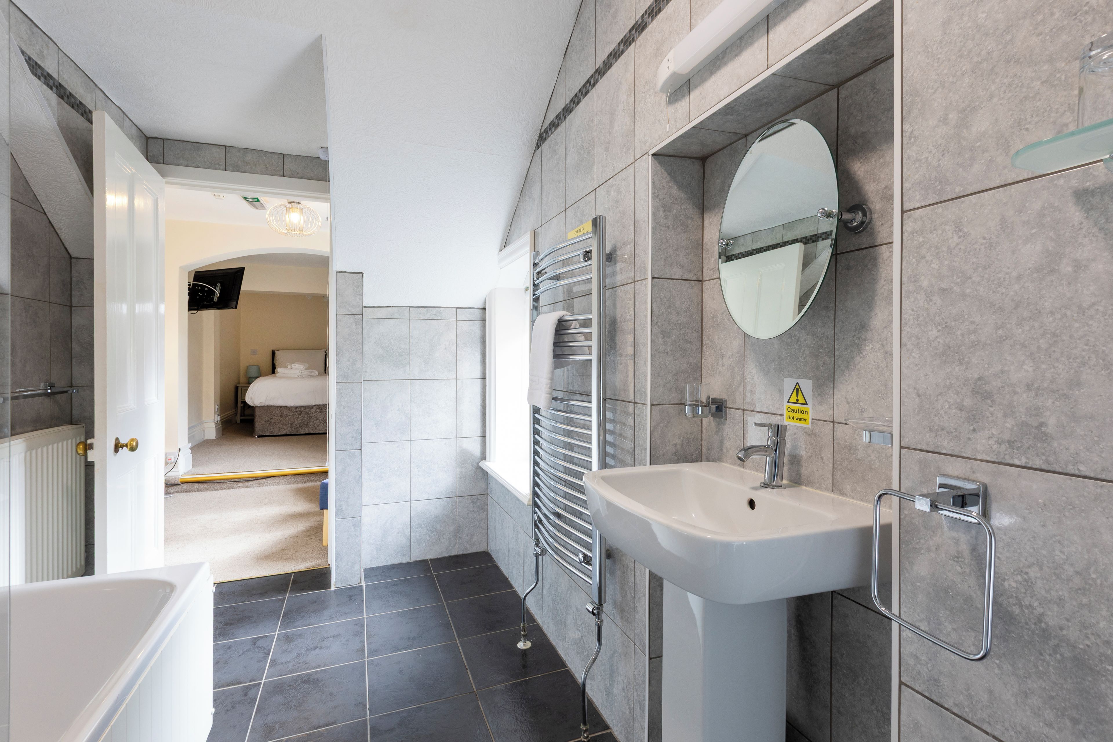 A modern bathroom with a white sink, a mirror, and a towel rack.