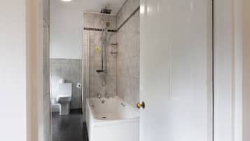 Un baño con bañera, inodoro y zona de ducha.