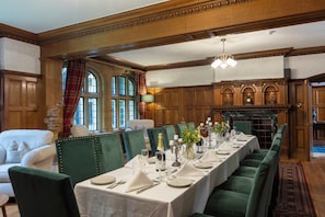 A formal dining room with a long table set for a meal, green upholstered chairs, and a fireplace in the background. - Dunsley Hall Country House Hotel (Whitby)