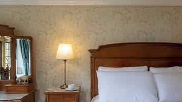 Une chambre d’hôtel avec un lit en bois, une table de chevet avec une lampe, un miroir et une commode.