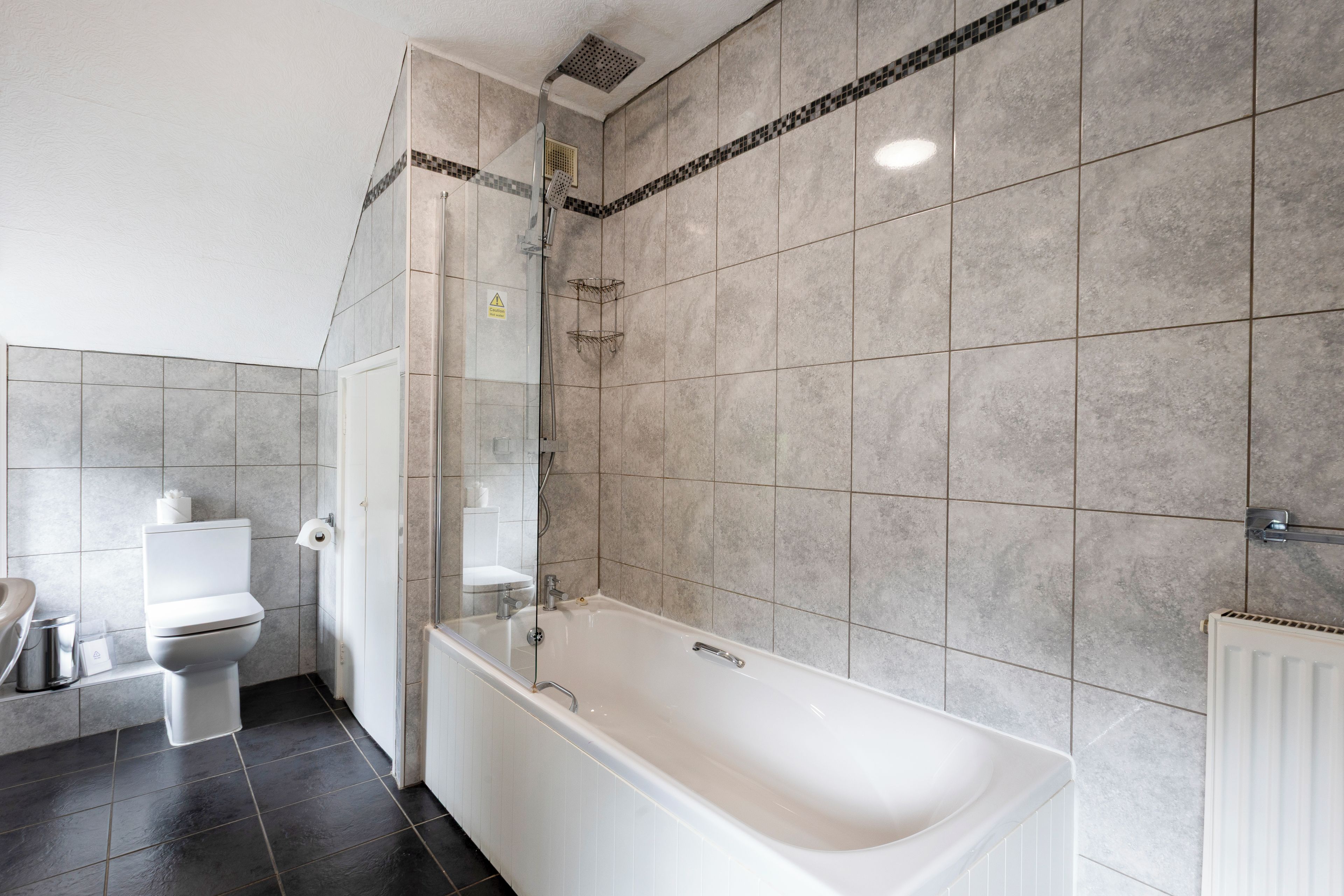 A modern bathroom with a bathtub, toilet, and shower area.