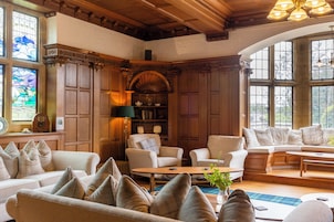 A cozy room with wooden paneling, a fireplace, and a large window.
