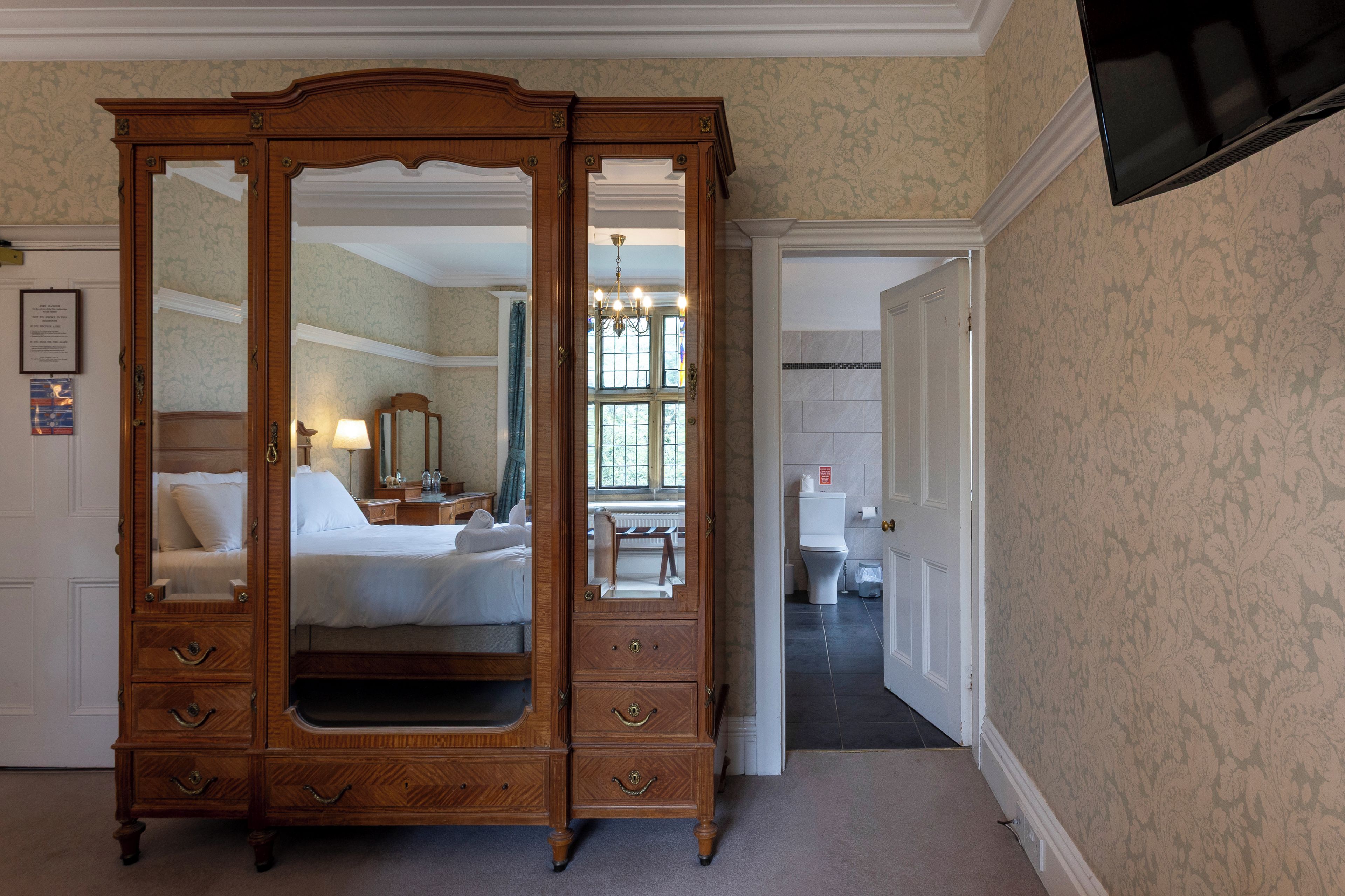 Un dormitorio con un aparador de madera grande, una cama, un tocador y un espejo.