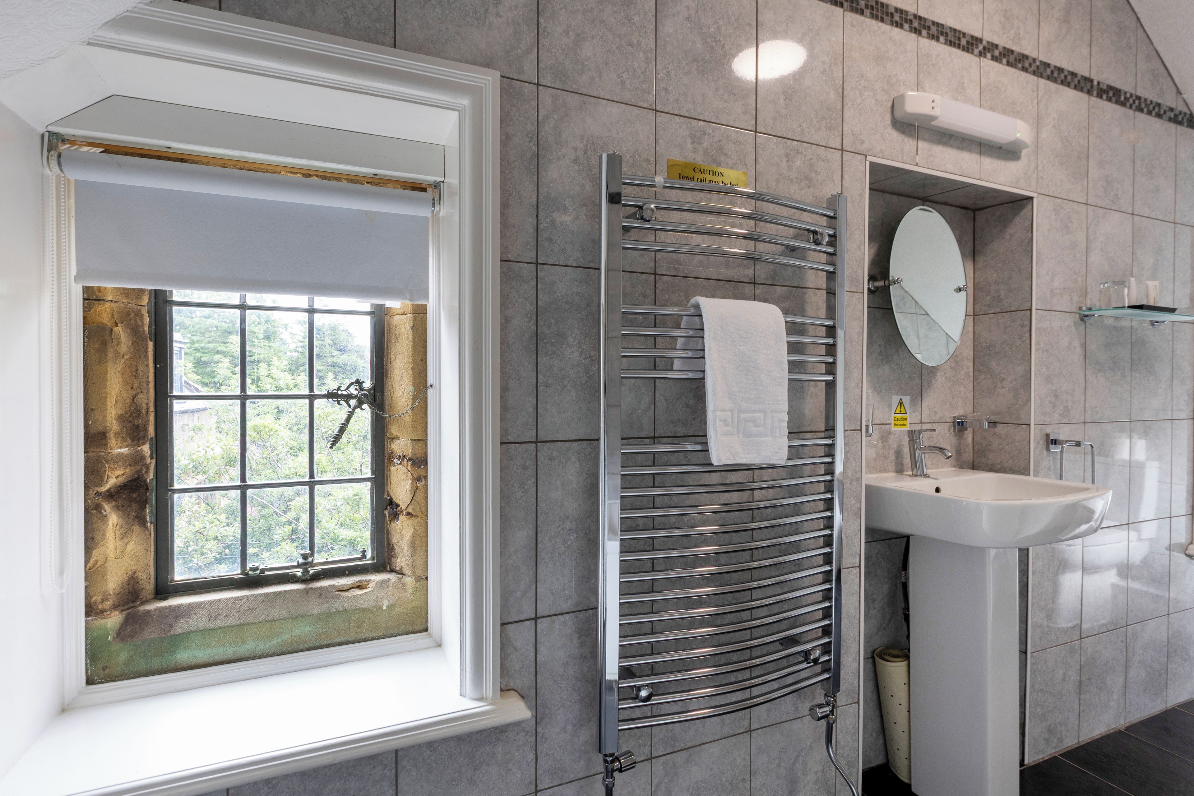 A bathroom with a window, towel rack, mirror, and sink.