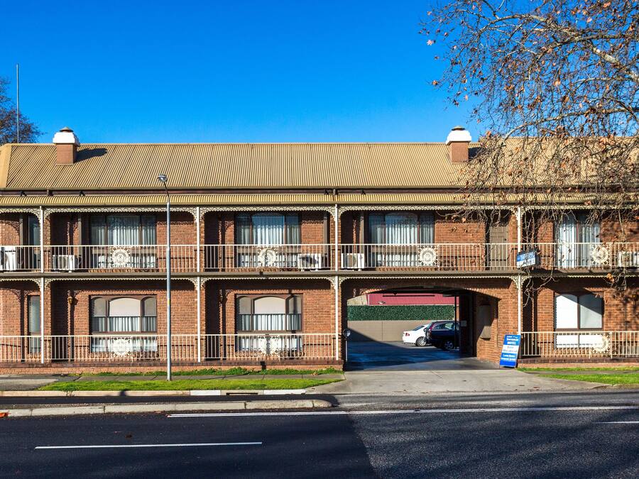 A two-story motel with a balcony on the second floor, a covered entrance, and a sign indicating it is a motel.