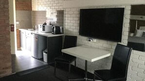A modern kitchen with a flat-screen TV, a dining table, and black chairs. - Albury Townhouse Motel (Albury)