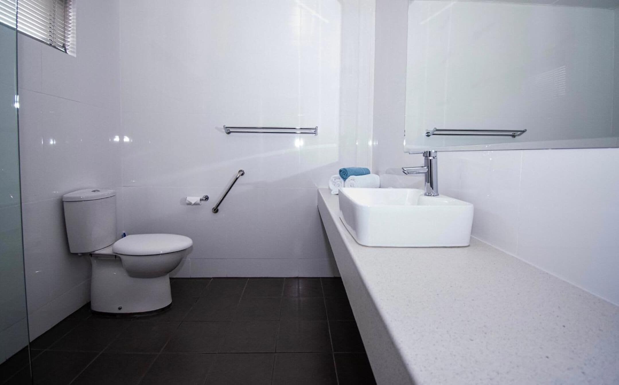 A modern bathroom with a toilet, sink, and towel rack.