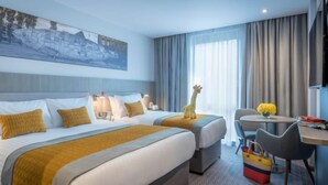 Habitación de hotel con dos camas, un escritorio, una silla y una estatua de jirafa.