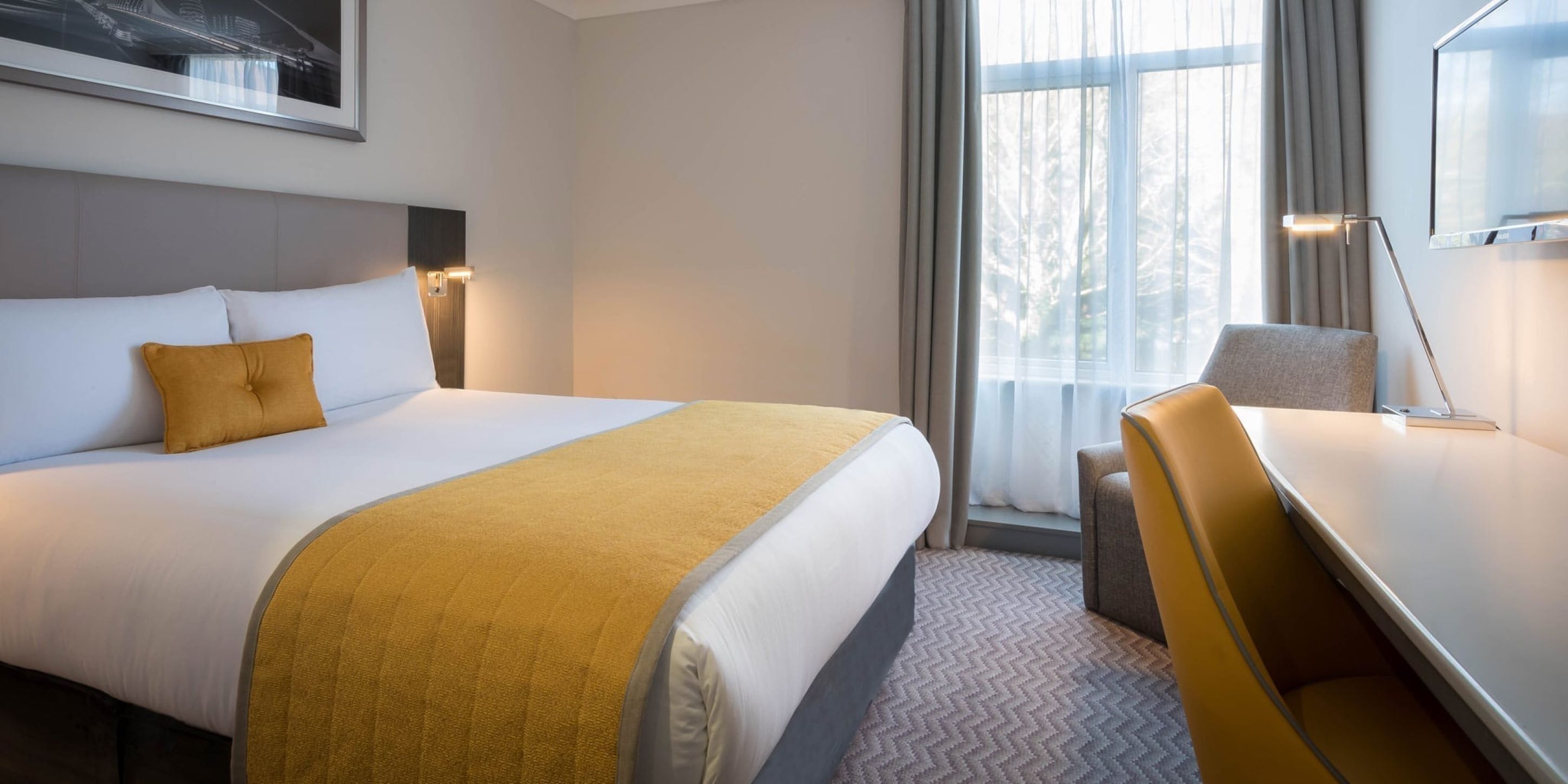 Una habitación de hotel con una cama, un escritorio y una silla.