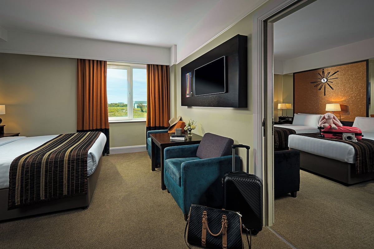 Een hotelkamer met twee bedden, een bank, een televisie en uitzicht op het omliggende landschap.