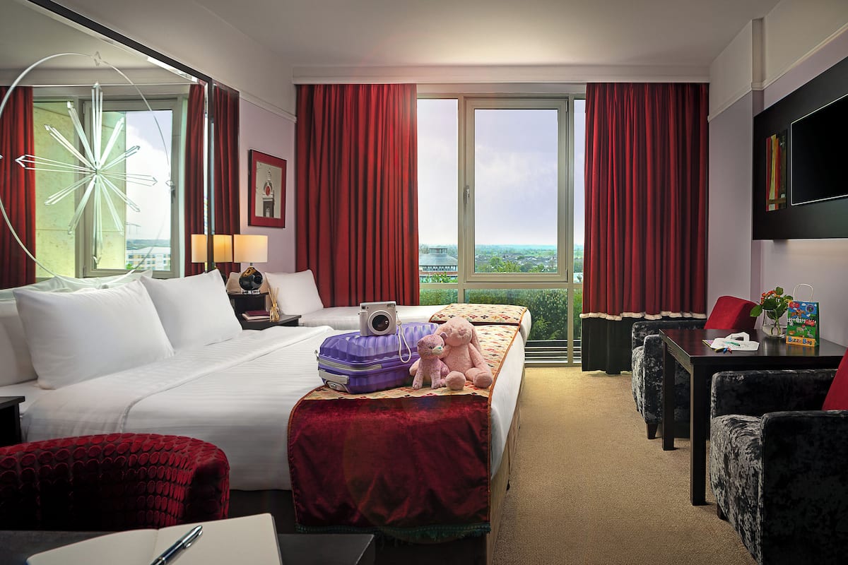 Een hotelkamer met een bed, een bureau, een stoel en een groot raam met gordijnen.