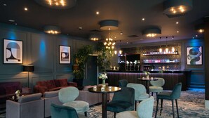 A modern lounge area with sofas, armchairs, and a bar.
