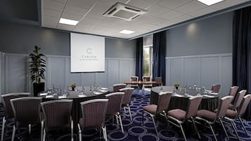 A conference room with a presentation screen, round tables, and chairs.