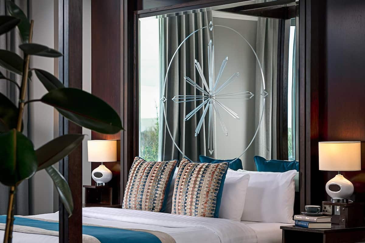 Een moderne hotelkamer met een groot bed, een decoratieve plafondlamp en een potplant.