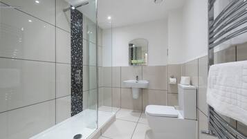A modern bathroom with a glass shower enclosure, a white toilet, and a sink.