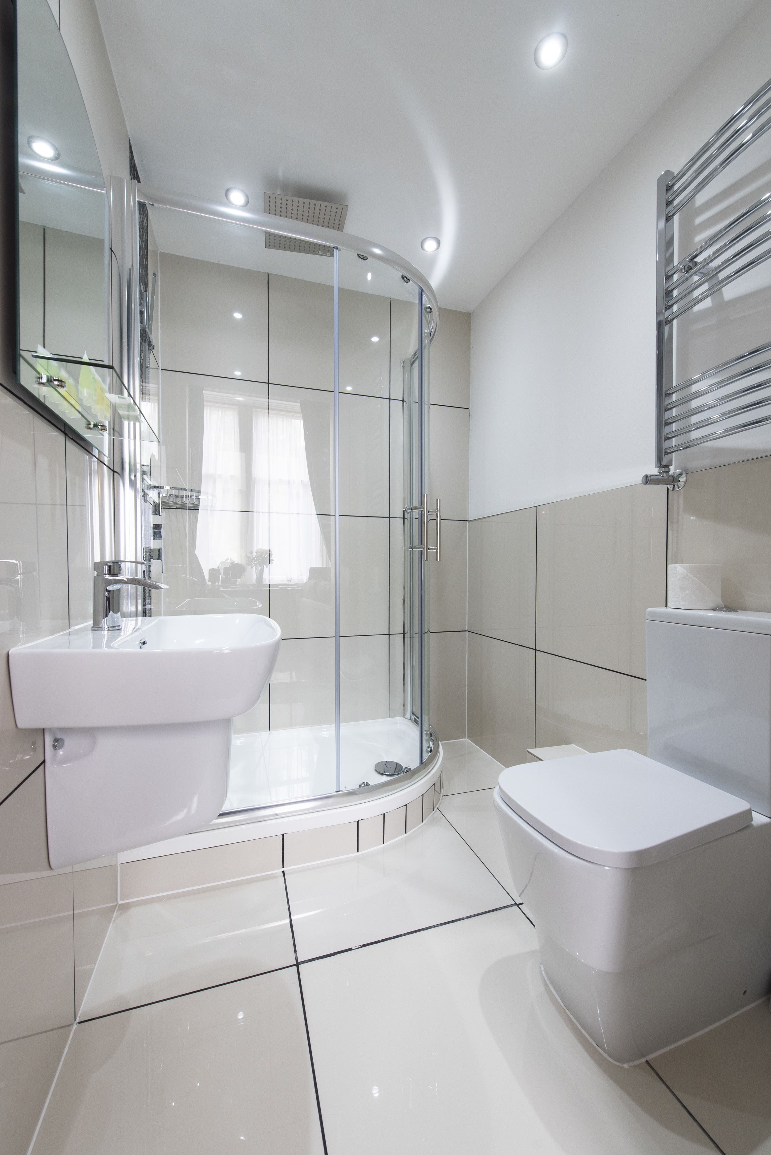 A modern bathroom with a glass-enclosed shower, a white sink, and a toilet.