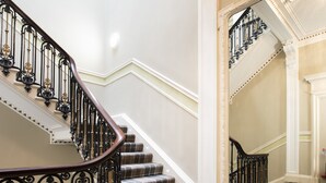 A grand staircase with ornate black railings and a checkered carpet. - Grosvenor Suites (Edinburgh)