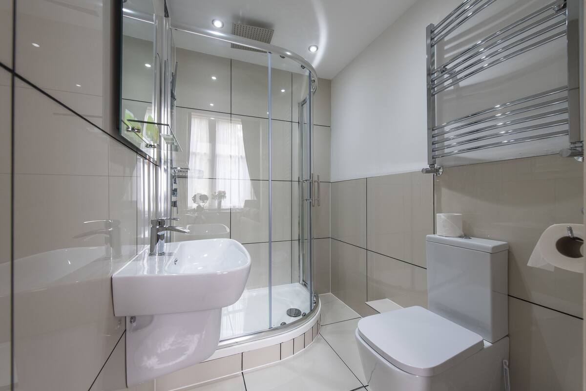 A modern bathroom with a glass-enclosed shower, a white sink, and a toilet.