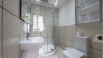A modern bathroom with a glass-enclosed shower, a white sink, and a toilet.