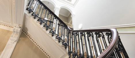 A grand staircase with ornate black balustrades and white walls.