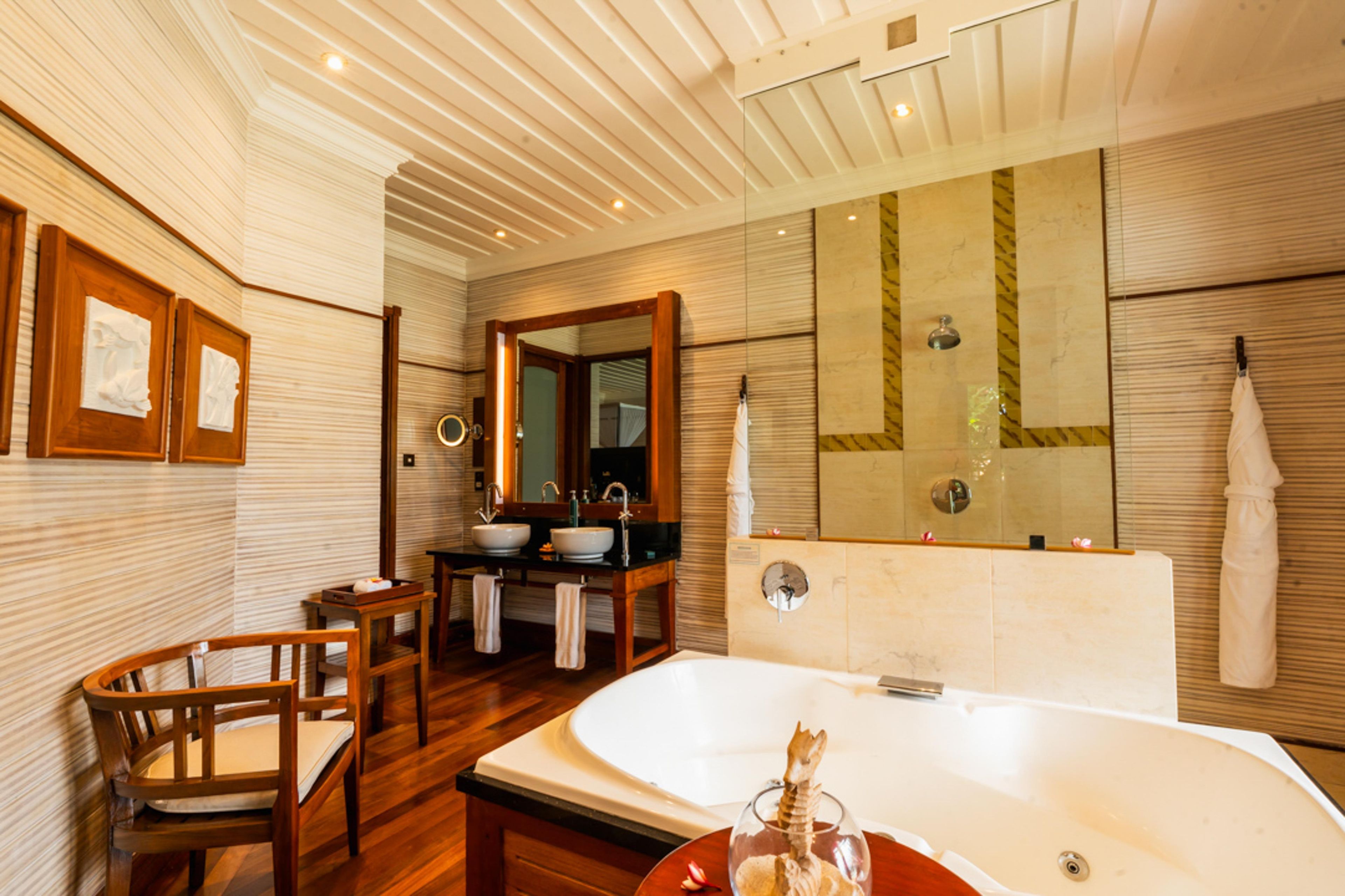 A bathroom with a bathtub, two sinks, a mirror, and a wooden chair.